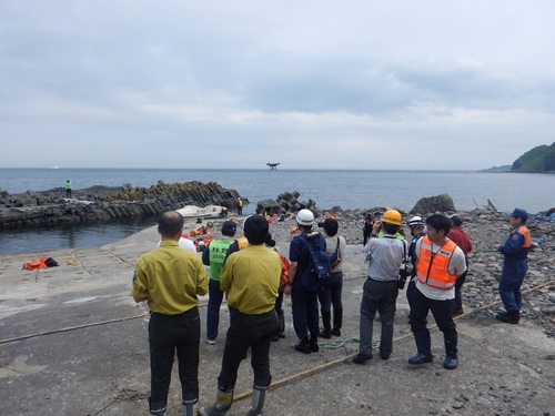 波止場周辺からドローンを飛ばし、岩陰に隠れた遭難者役を探す（2019年7月撮影）